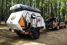 an off road camper parked in the woods next to a truck with its trailer attached