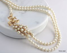 three strand pearl necklace with gold tone flower and leaves on white marble slabd surface