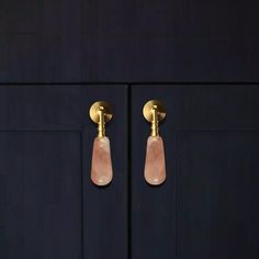 two gold handles on a black cabinet with pink stone knobs in the middle and bottom