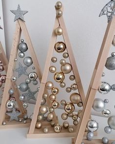 three wooden christmas trees with ornaments on them