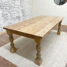 a wooden table sitting on top of a white rug in front of a brick wall