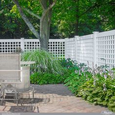 a white fenced in area with chairs and plants