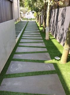 the walkway is lined with artificial grass between two buildings, and there are trees on either side