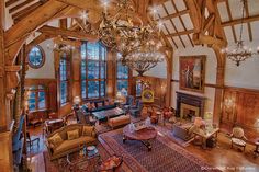 the large living room is decorated in wood and has chandeliers hanging from the ceiling