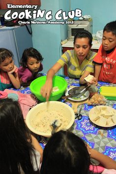 a group of children sitting around a table with food in bowls on top of it