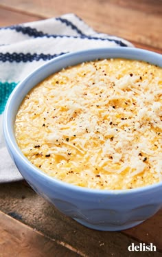 a blue bowl filled with cheese on top of a wooden table