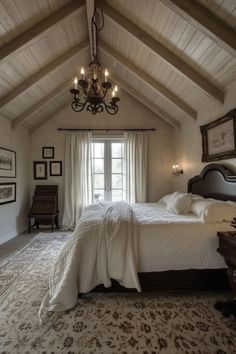 a large bed sitting under a chandelier in a bedroom next to a window