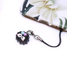 a cell phone case with a flower on it and a keychain attached to it