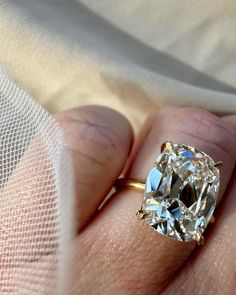 a close up of a person's hand holding a ring with a diamond in it