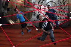 three men are running through a room with red lines