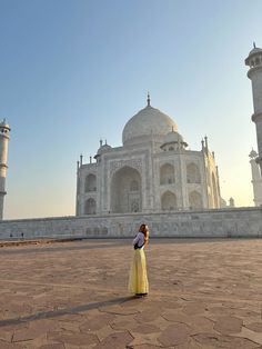 a woman standing in front of the tajwa mosque, with her back turned to the camera