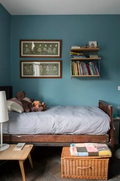 a bedroom with blue walls and a bed in the middle, two bookshelves on the wall