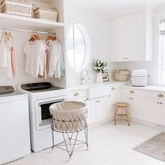 a white laundry room with clothes hanging on the rack