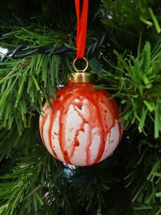 a red and white ornament hanging from a christmas tree