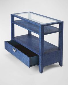 a blue table with drawers underneath it and a glass top on the bottom shelf that is open