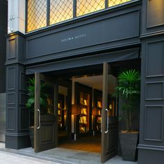 an entrance to a hotel with potted plants and bookshelves on either side