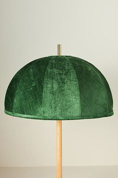 a green lamp shade sitting on top of a wooden stick