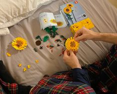 a man laying on top of a bed next to yellow sunflowers and legos