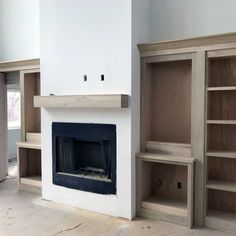 an empty living room with built in bookcases and a fireplace that is white