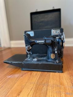 an old black sewing machine sitting on top of a wooden floor next to a case