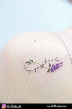 the back of a woman's shoulder with purple flowers on it and her name written in cursive writing