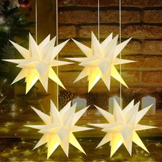 five white stars hanging from strings in front of a fireplace