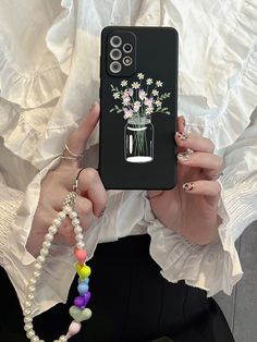 a woman holding up her phone case with flowers in a vase on it