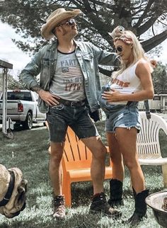 a man and woman standing next to each other in front of a fire pit with a dog