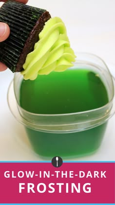 a hand is holding a green substance in a container with the words glow - in - the - dark frosting on it