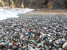 a beach covered in lots of glass next to the ocean with text that reads smooth glass pieces on glass beach, near fort bagg, california