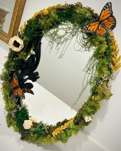 a mirror with moss and butterflies on it