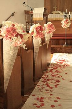 several vases with flowers on a table in front of a church pew and alter