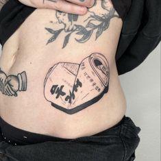 a woman with tattoos on her stomach has a can of beer in the shape of a heart