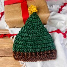 a crocheted christmas tree hat next to a wrapped present