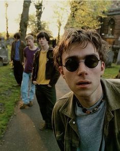 a group of young men walking down a sidewalk in front of a cemetery with tombstones