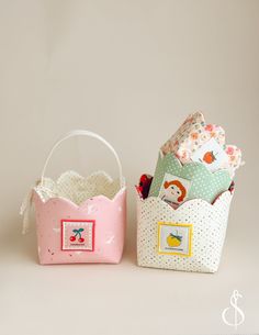 two small baskets are sitting next to each other on a white surface, one is pink and the other is green