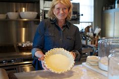 a woman is holding a pie pan in the kitchen with other baking supplies on the counter