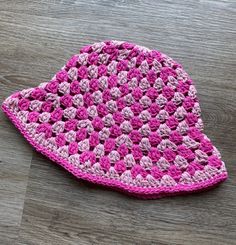 a pink crocheted hat sitting on top of a wooden floor