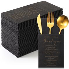 a stack of black napkins with gold forks and spoons on top of it