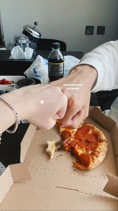 a person grabbing a slice of pizza from a box