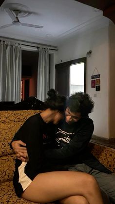 two people sitting on top of a couch in a living room next to each other