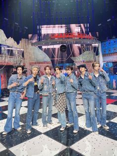 a group of young men standing on top of a checkered floor with their hands in the air