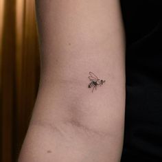 a small tattoo on the arm of a woman with a bee on it's back