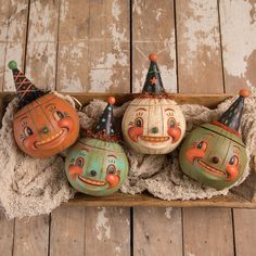 four painted pumpkins sitting on top of a wooden box with faces drawn on them