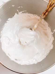 a mixing bowl with whipped cream and two golden spoons