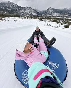 two people are sledding down a snowy hill