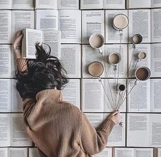 a woman laying on top of an open book next to flowers and bookshelves