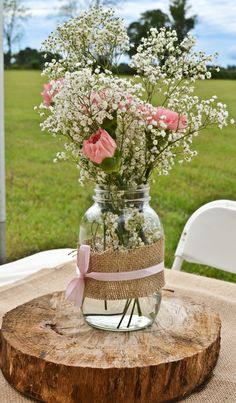 a vase filled with flowers sitting on top of a wooden table next to a field