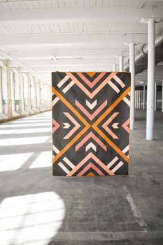 a large black and orange piece of art in an empty space with columns on both sides