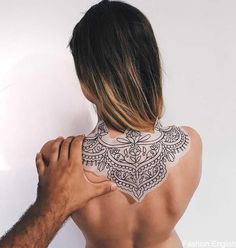 the back of a man's upper half with tattoos on his neck and shoulder